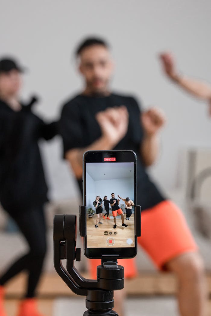 A group of people recording a dance video using a smartphone indoors.